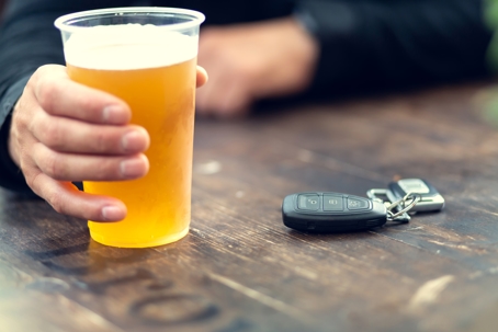 person holding a beer with car keys nearby