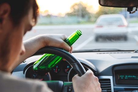 person driving with bottle of alcohol