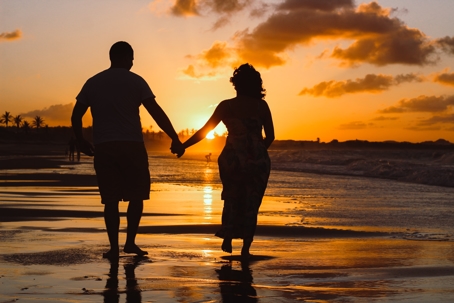 couple walking on beach at sunset